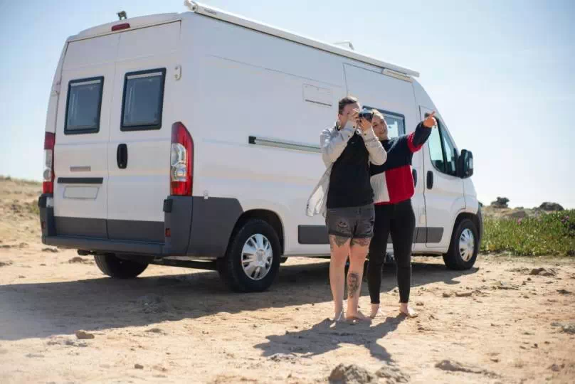 Para robiąca zdjęcie na plaży, w tle bus osobowy