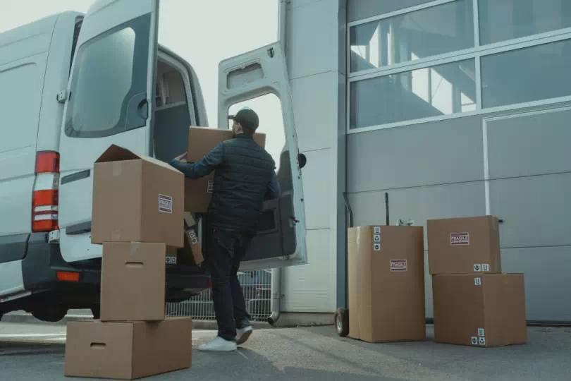 Mężczyzna pakujący kartony do samochodu dostawczego